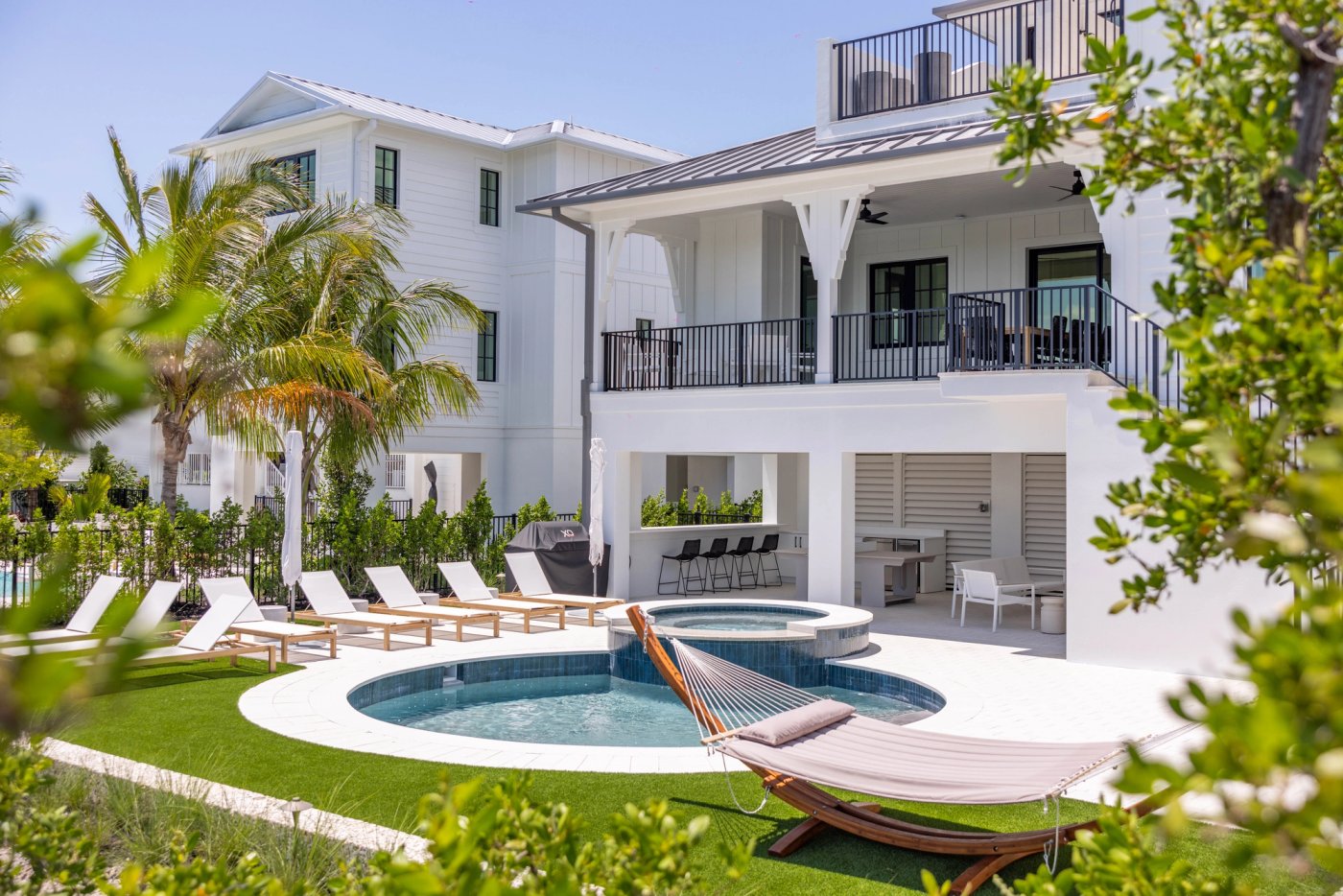 Lunara Bay house exterior with a pool, balconies, and tropical landscaping